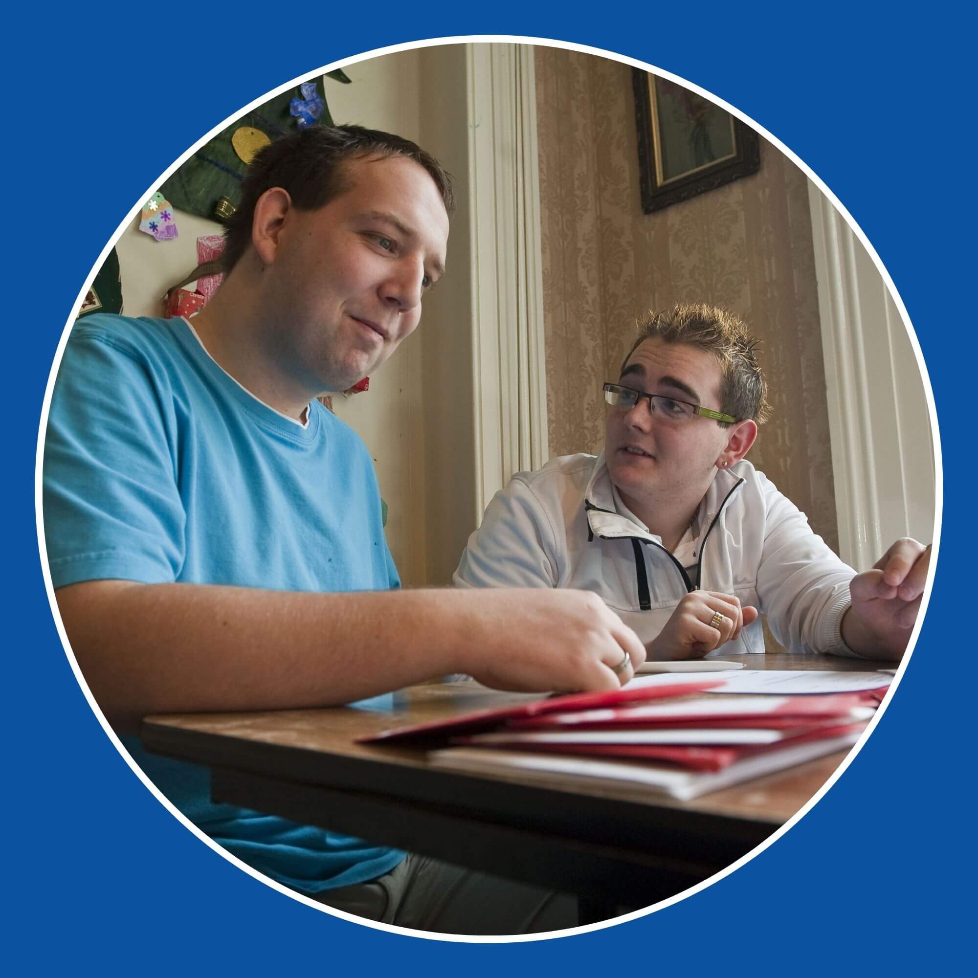 Two men sitting at a table discussing the paperwork on the table