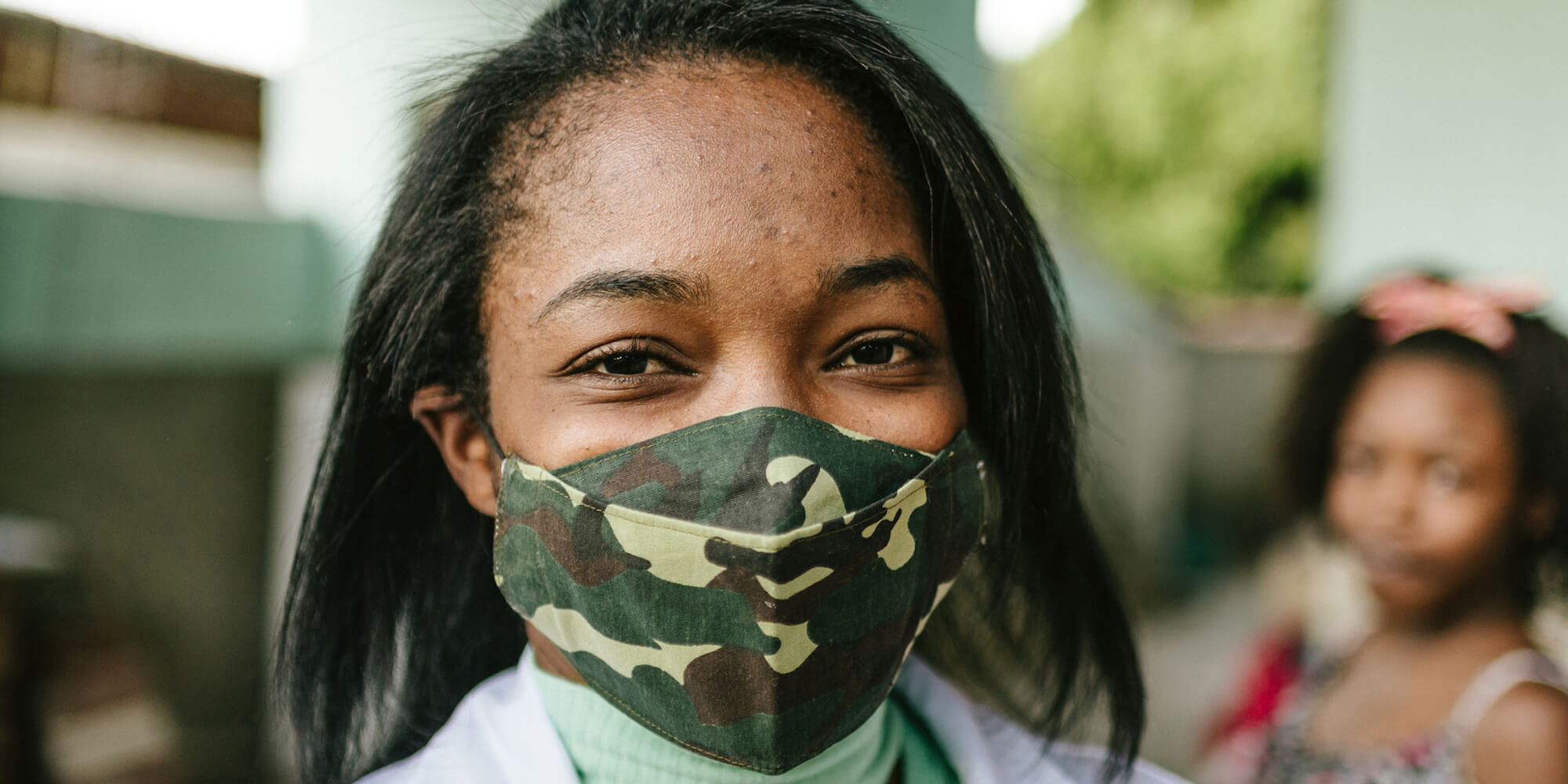 A young mother with her daughter in the background (image from iStock-1256332933)