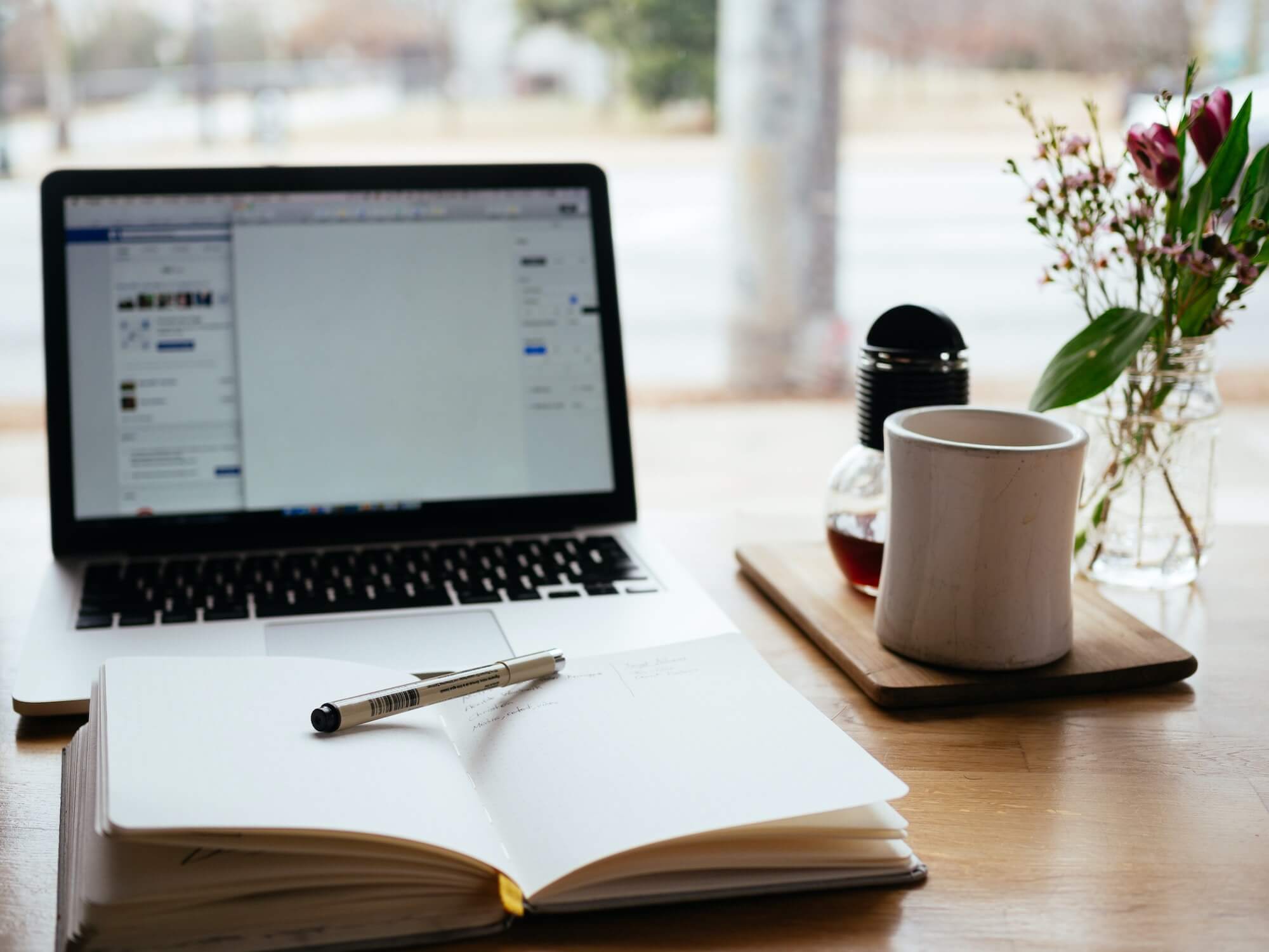 Image of a desk with a laptop, notepad and coffee (image from Unsplash by Nick Morrison)