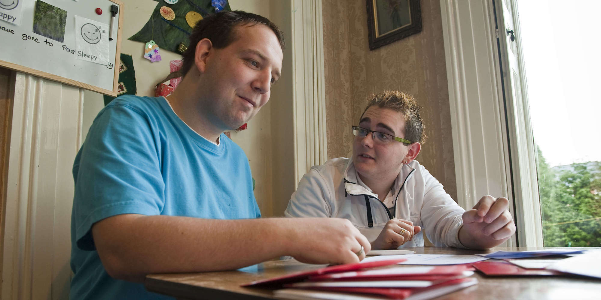 Two men sitting at a table discussing the paperwork on the table